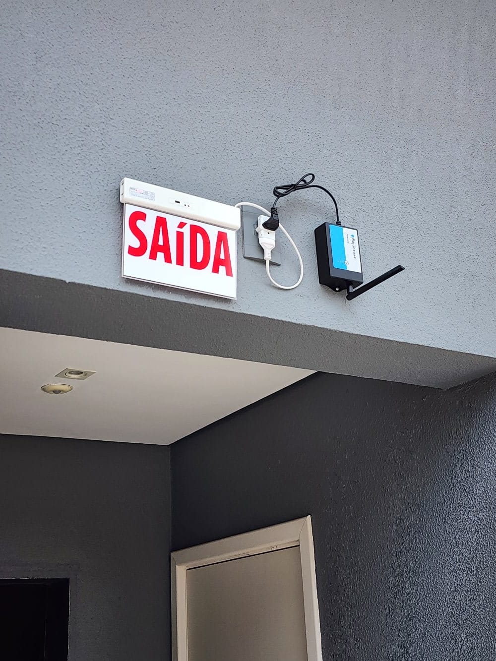 Gateway TeleNível instalado na parte superior de parede externa, ao lado de placa de saída